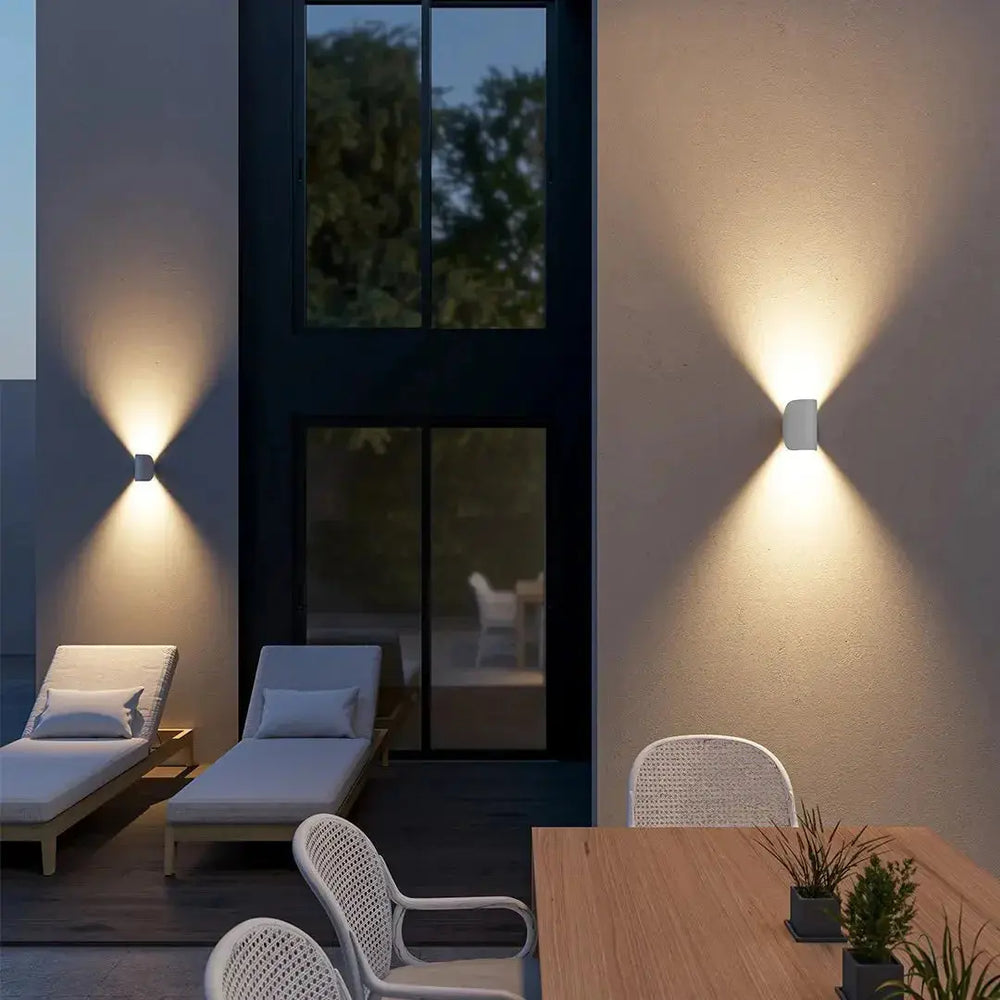 Two white Up & Down Modern Wall Sconces by Zenvia Essentials mounted on a wall in modern outdoor living space